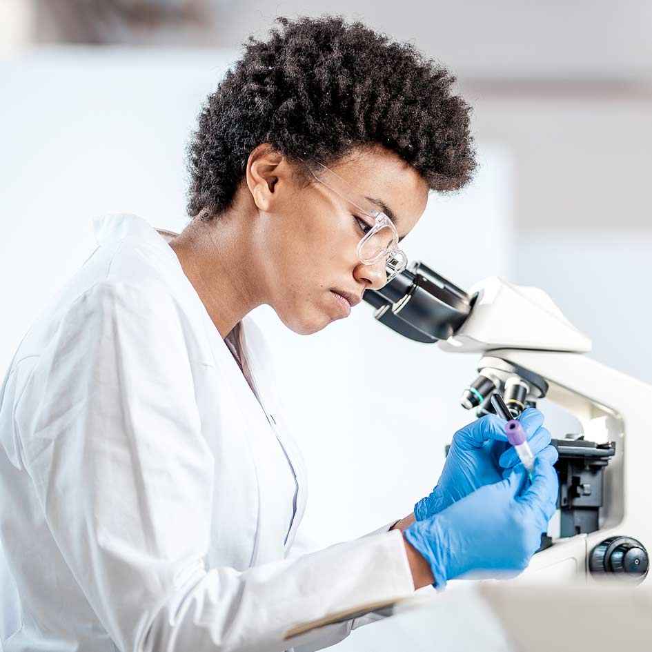 A woman in a laboratory next to a microscope
