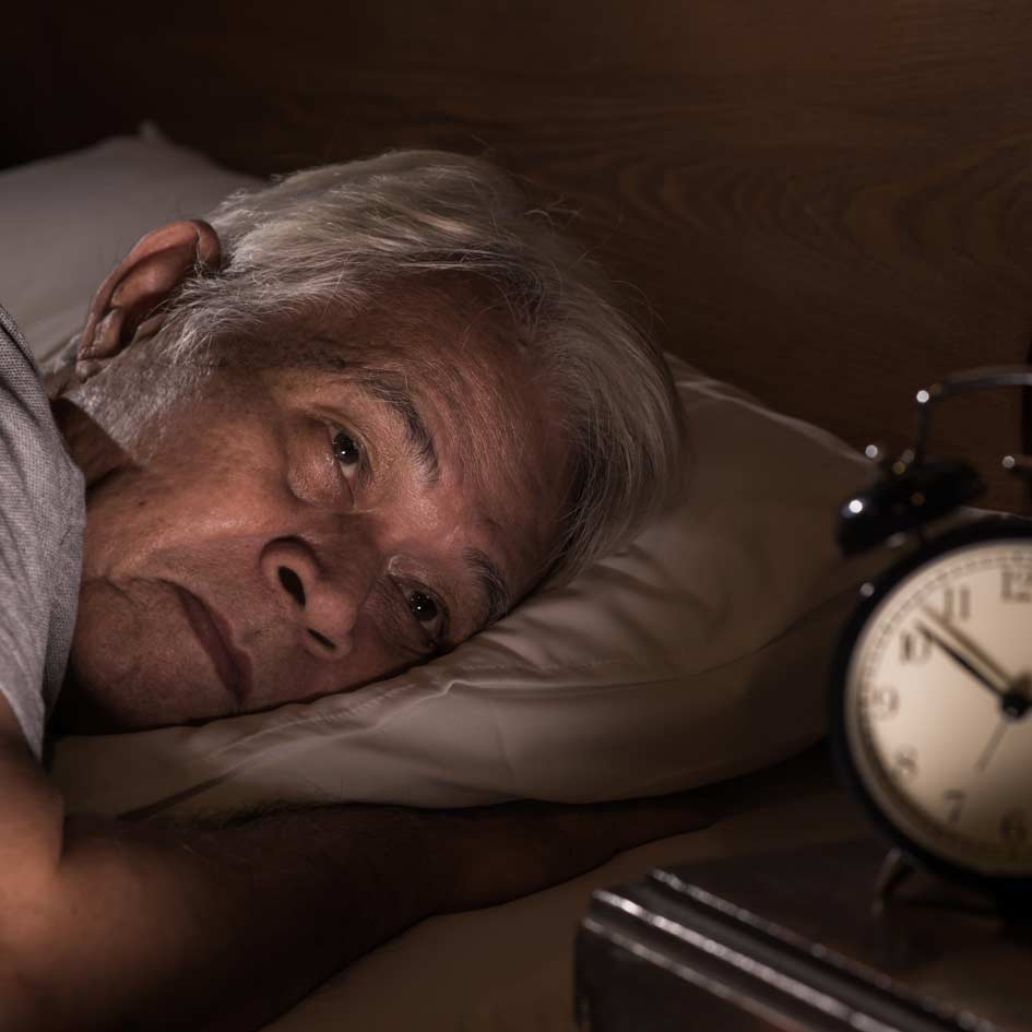 A man in bed looking at the clock